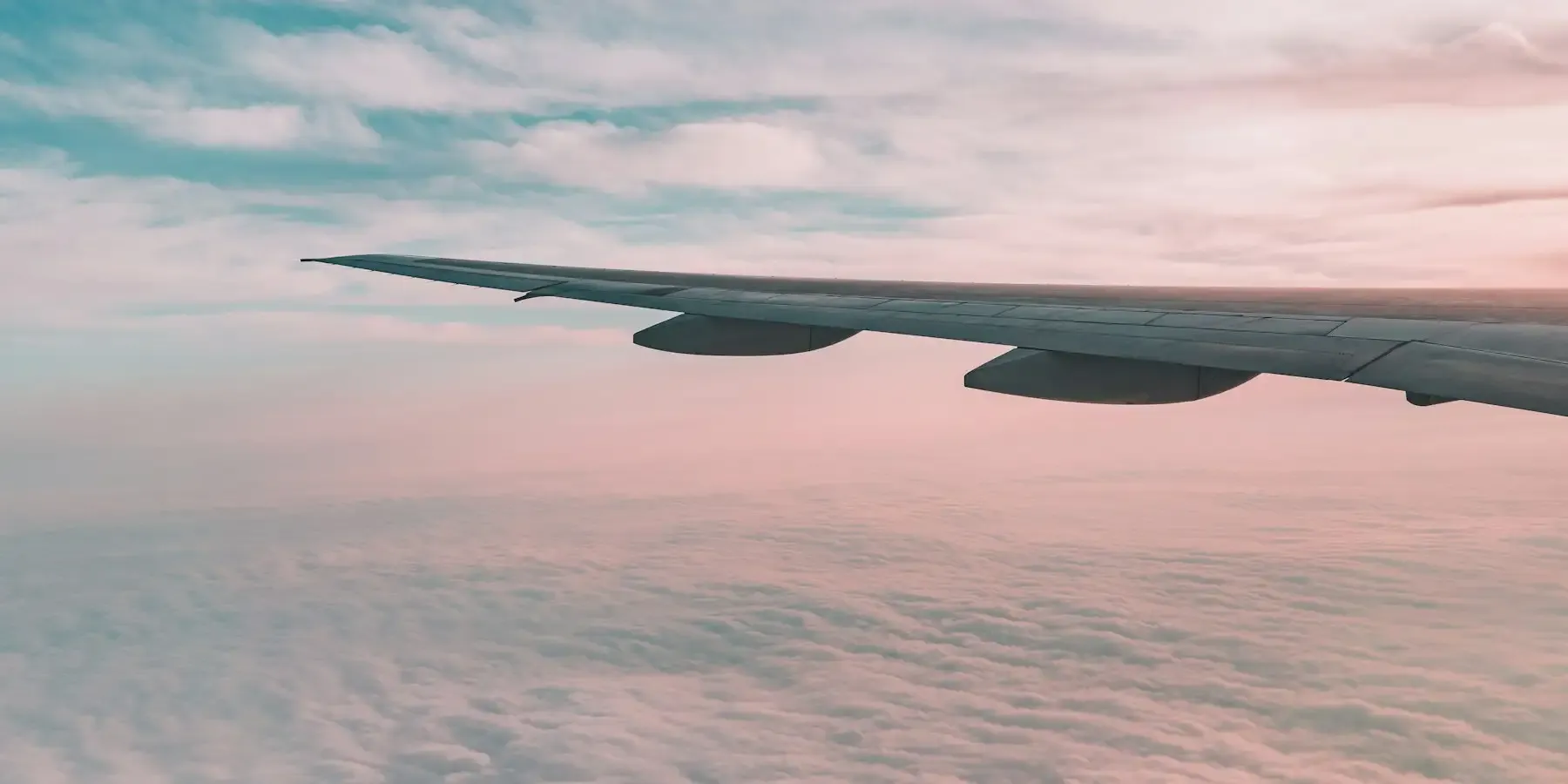An aircraft wing over cloud at sunrise
